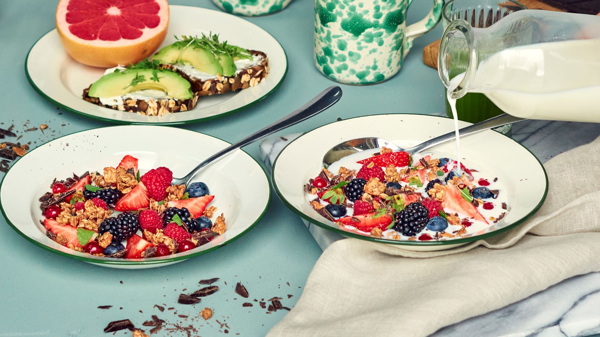 Granola med sommarbär och mörk choklad som serveras i en tallrik med mjölk