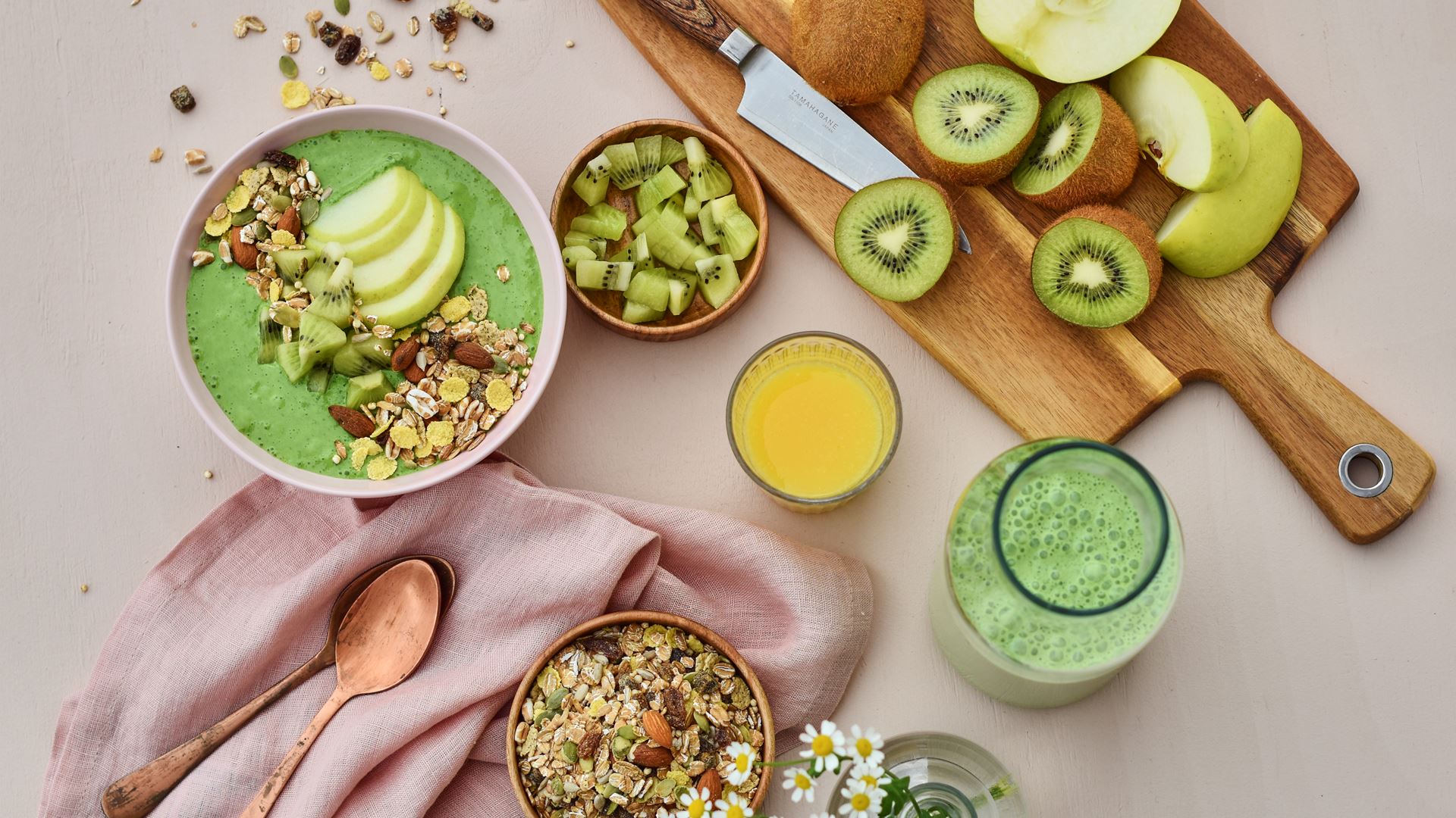 grön smoothiebowl serverad på ett bord med frukt